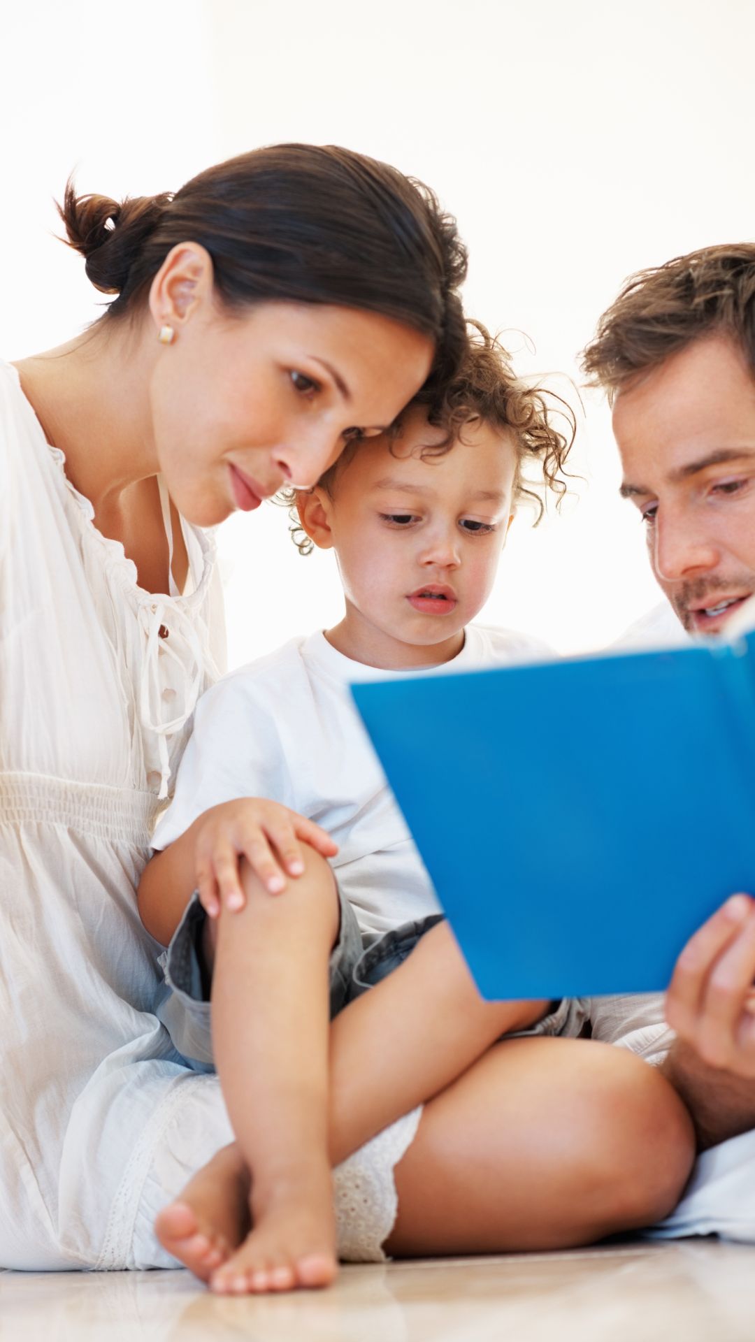 mama, papa e hijo leyendo un libro familiar